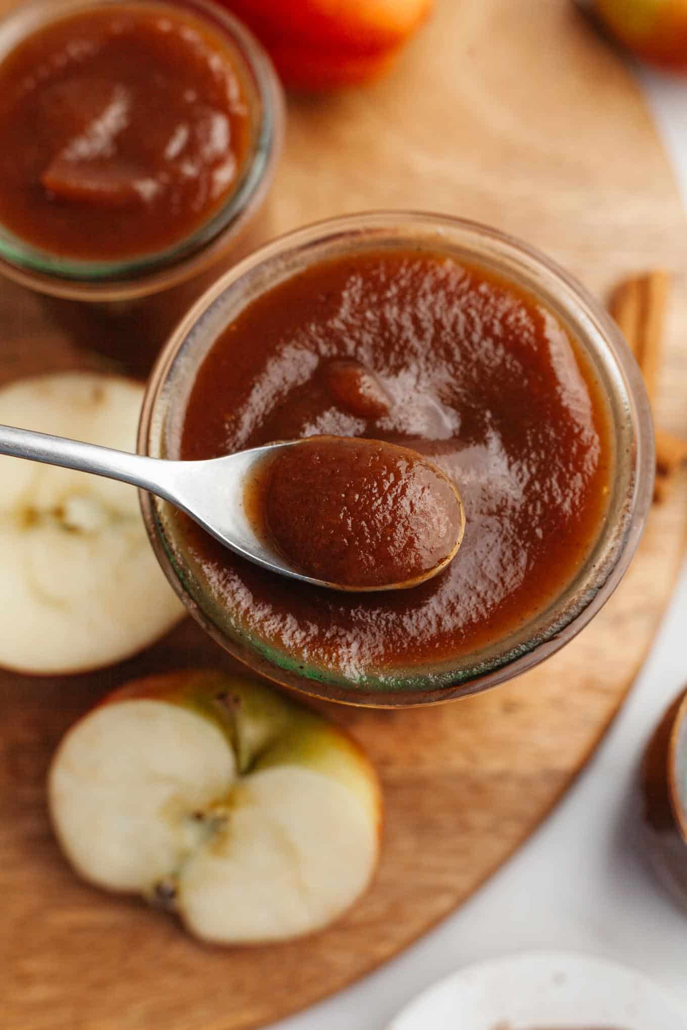 An overhead view of apple butter being spooned out of a glass jar.
