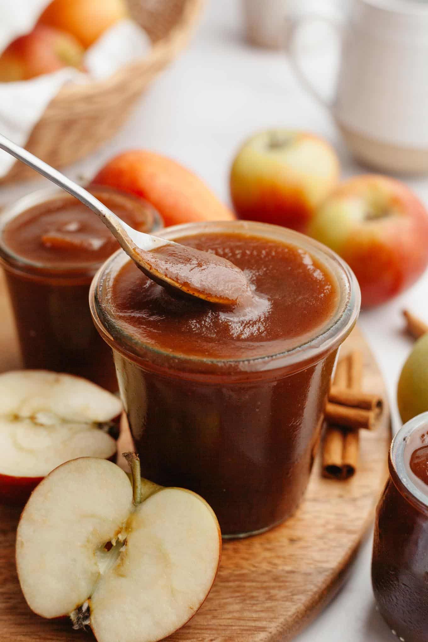 A side view of apple butter being spooned out of a glass jar. 