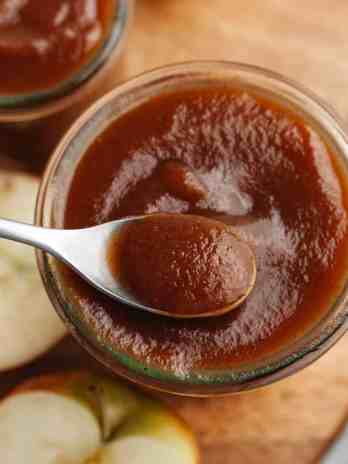 A jar of apple butter with a spoon resting on top.