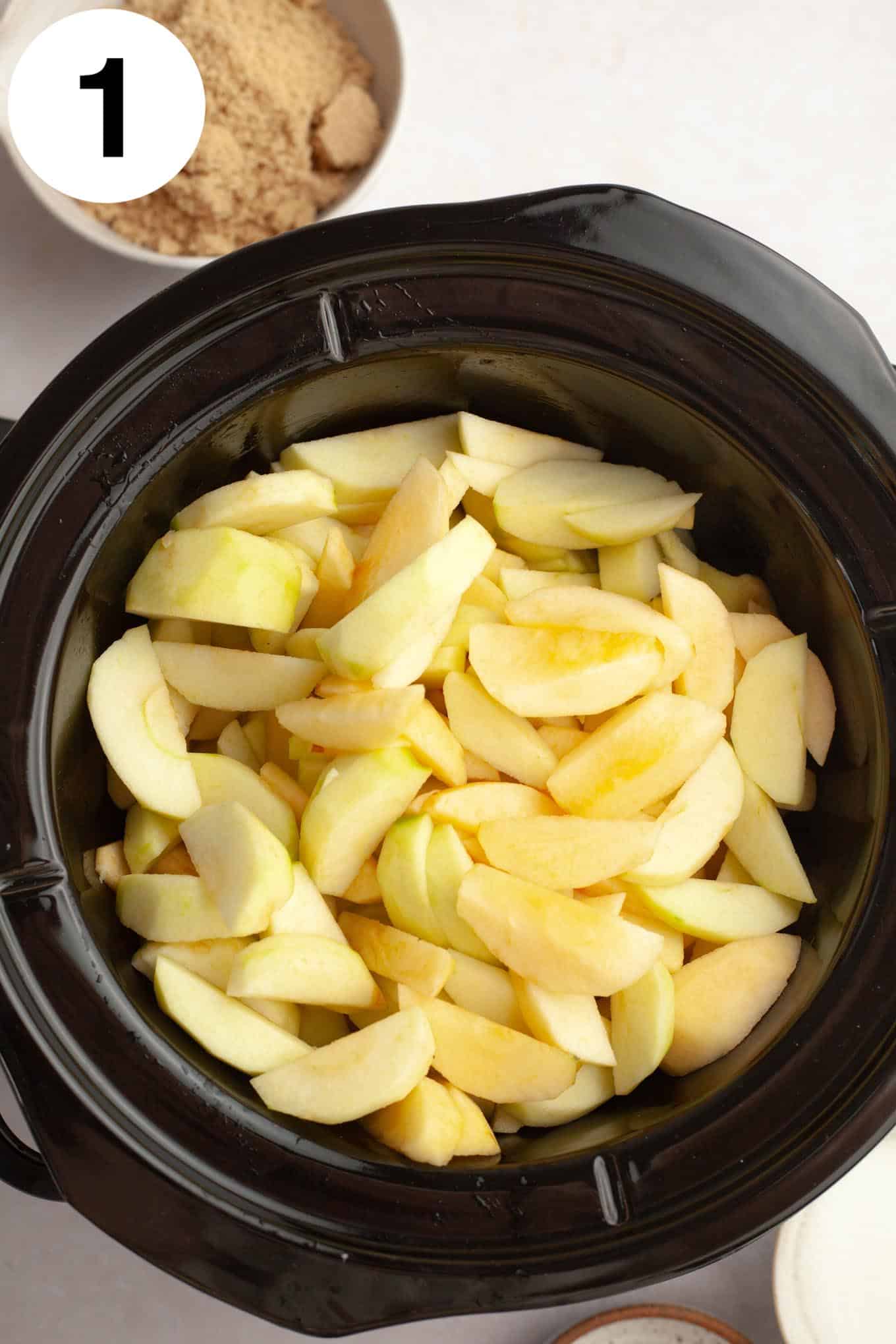 An overhead view of sliced apples in a Crockpot. 