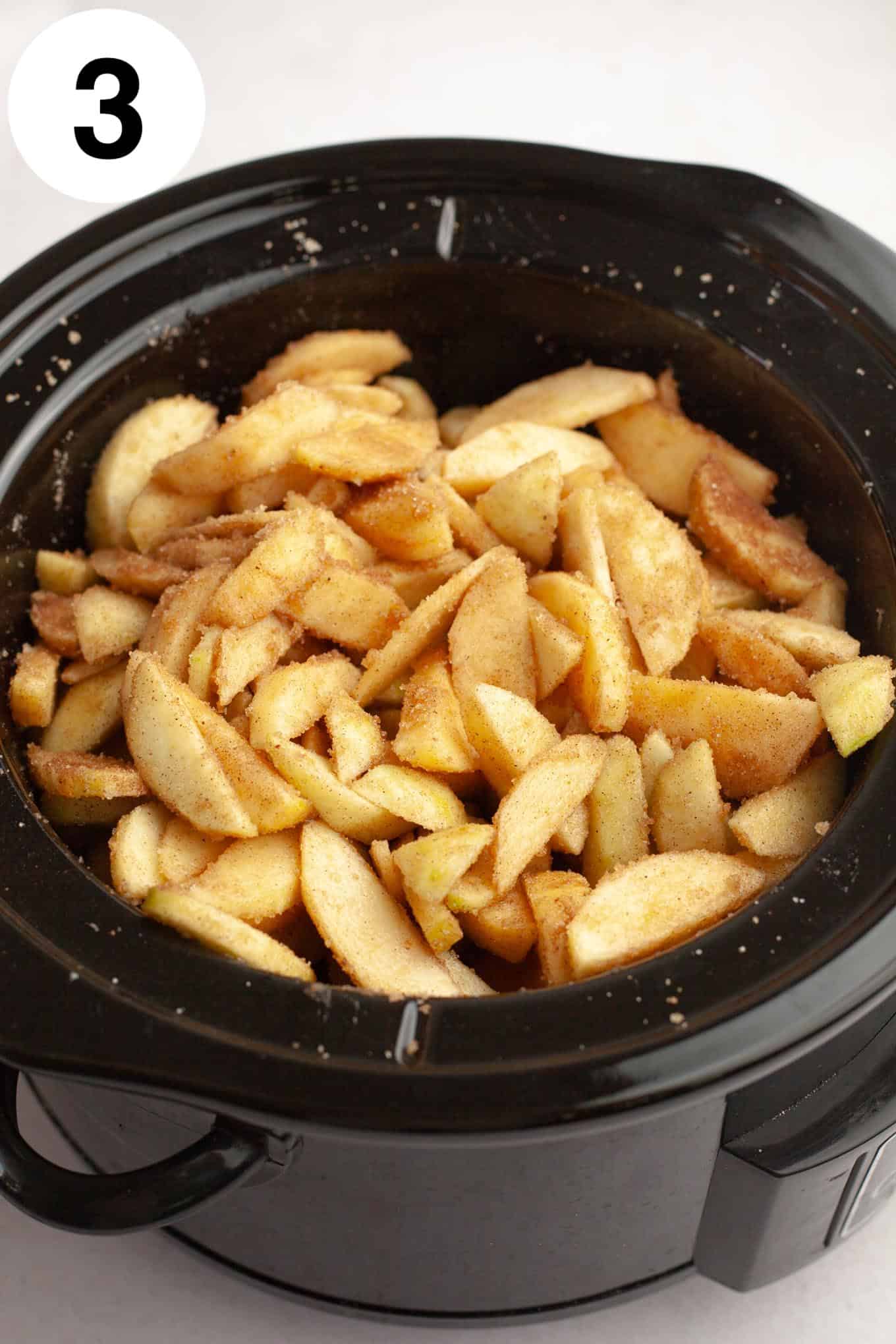 An overhead view of spiced apples in a Crockpot. 