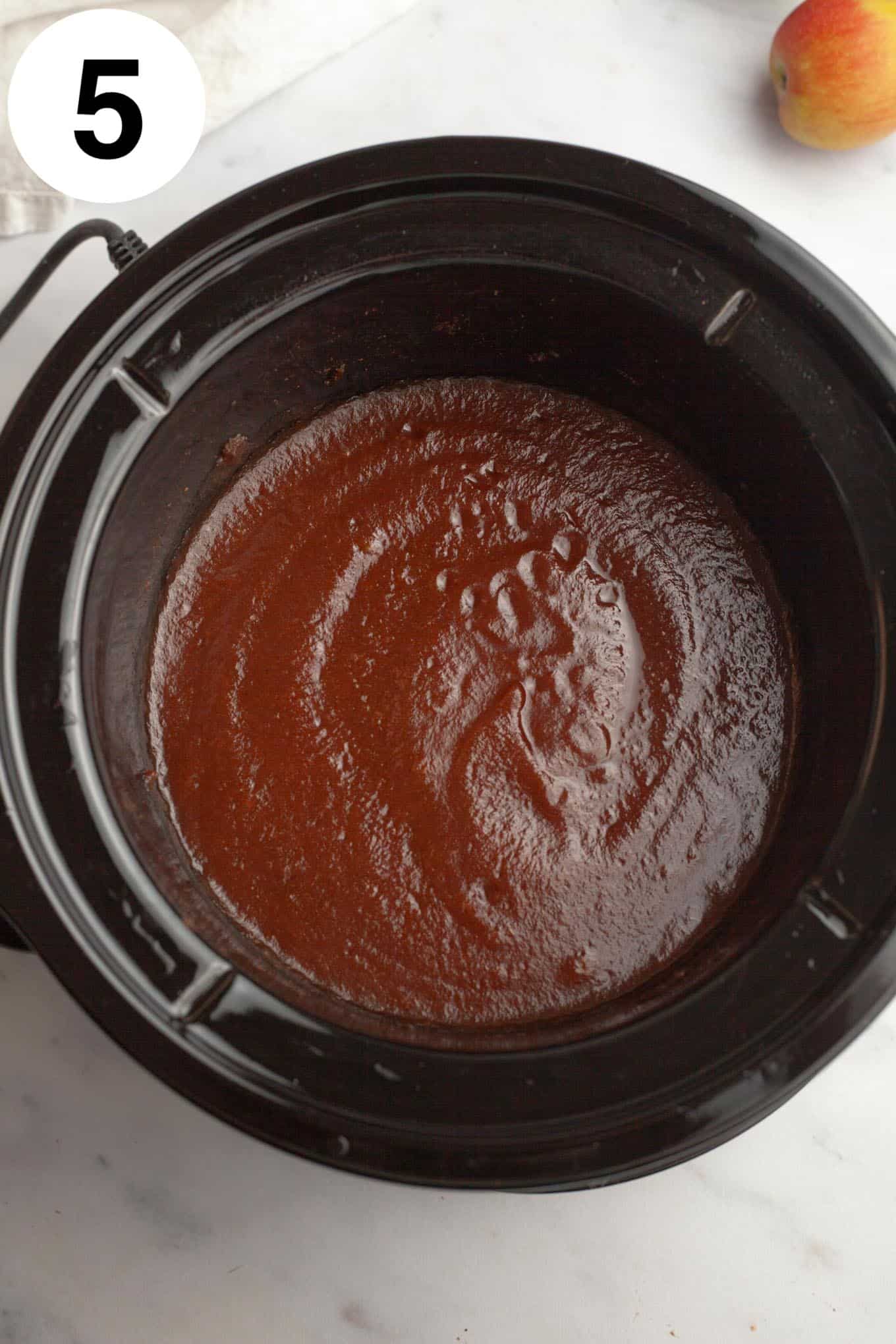 An overhead view of smooth apple butter in a Crockpot. 