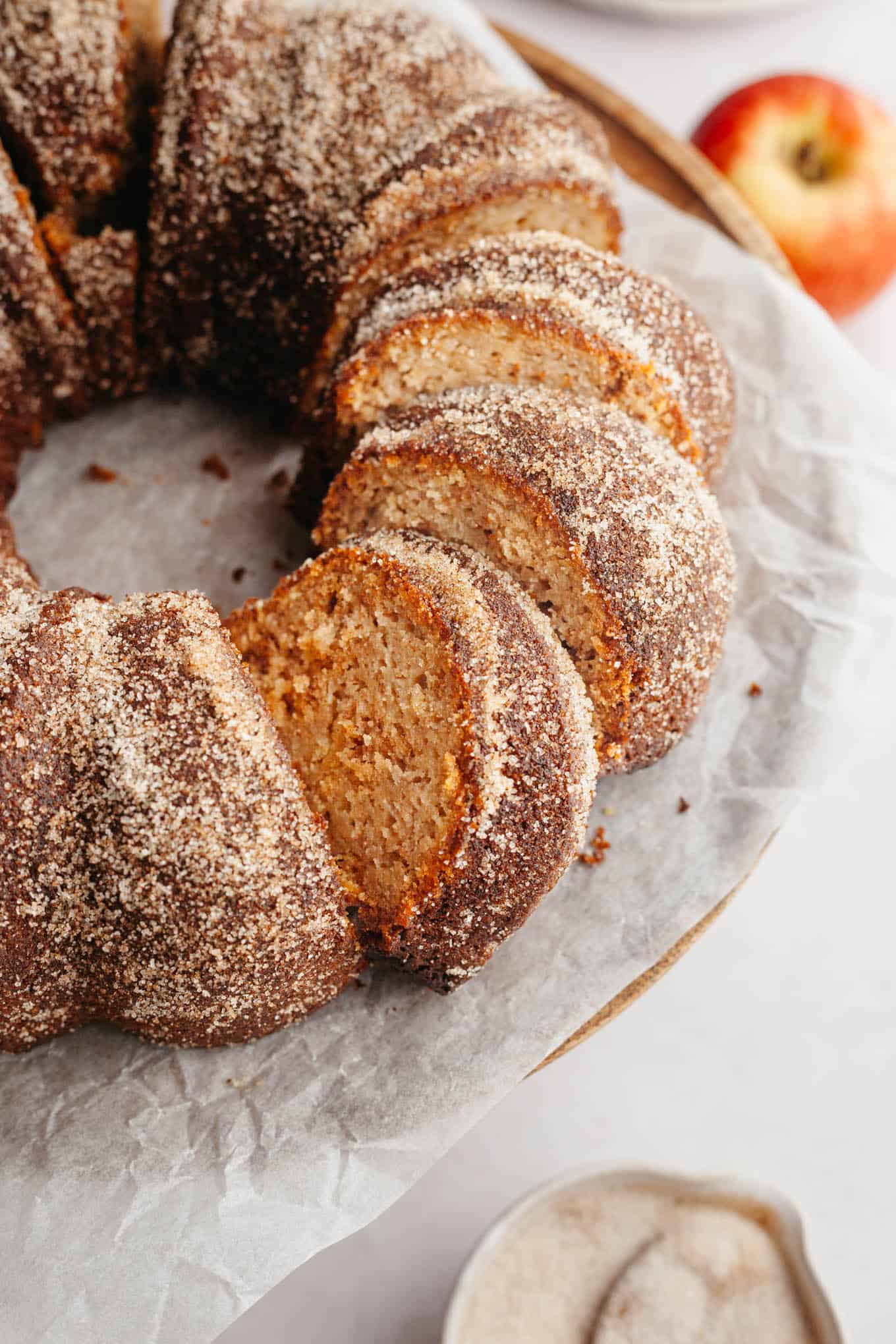 A sliced apple cider donut bundt cake on parchment paper.
