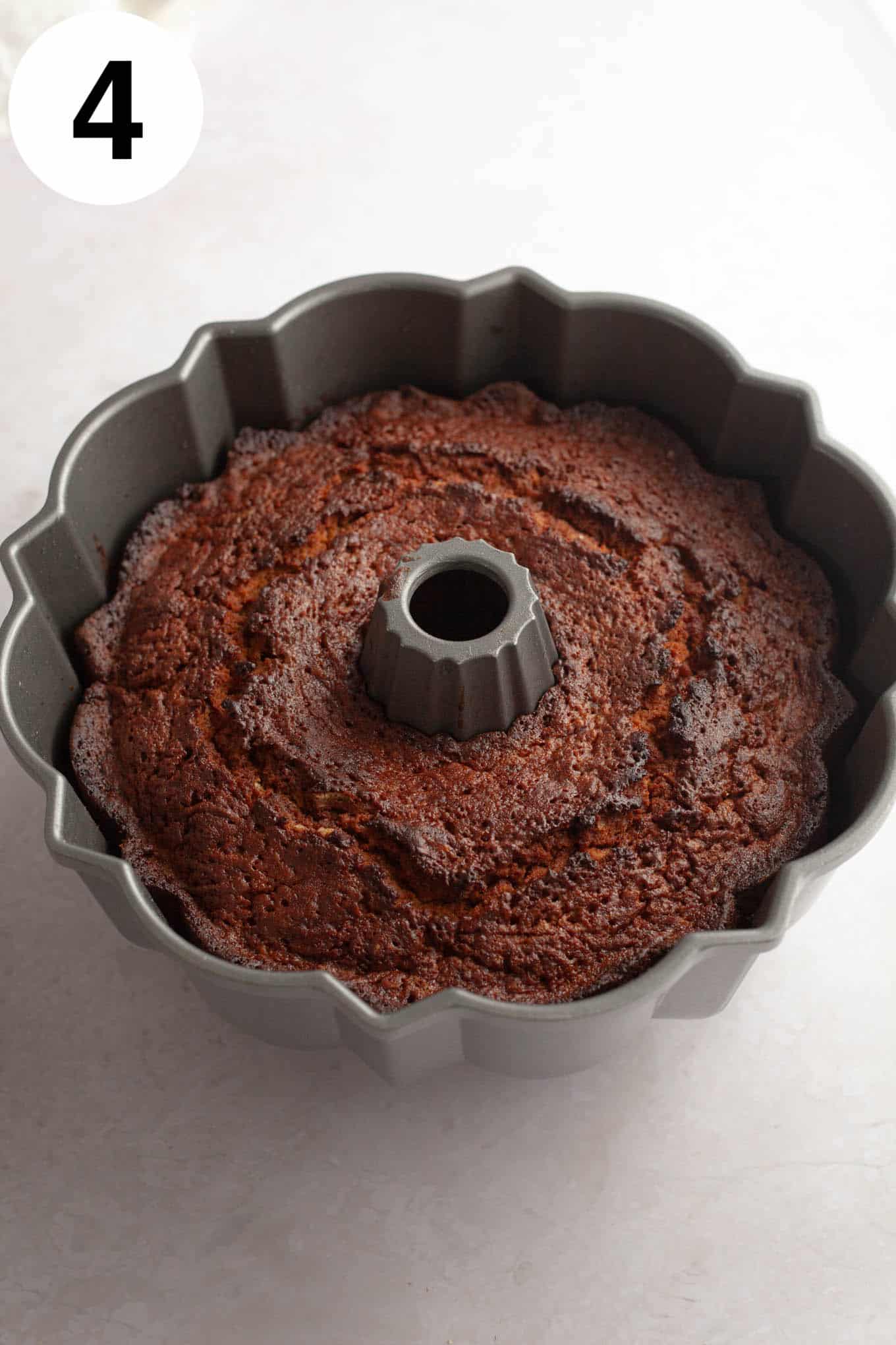 An overhead view of a baked apple cider donut cake in a bundt pan. 
