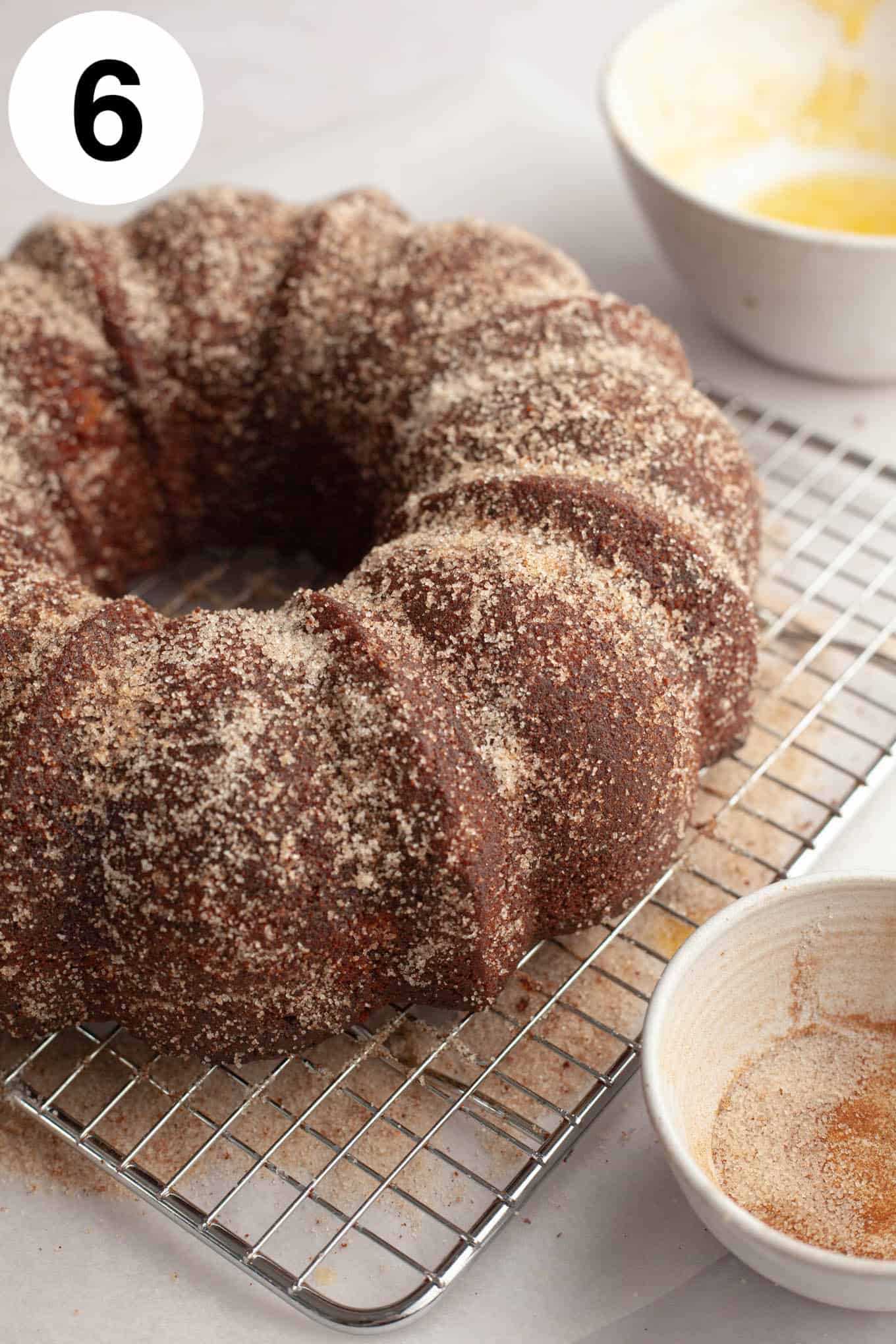 A cinnamon sugar-coated apple donut cake on a wire rack. 