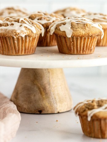 Apple muffins on top of a marble cake stand.