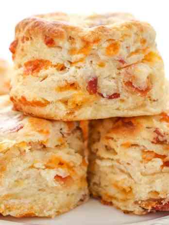 A stack of bacon cheddar biscuits on a white plate.