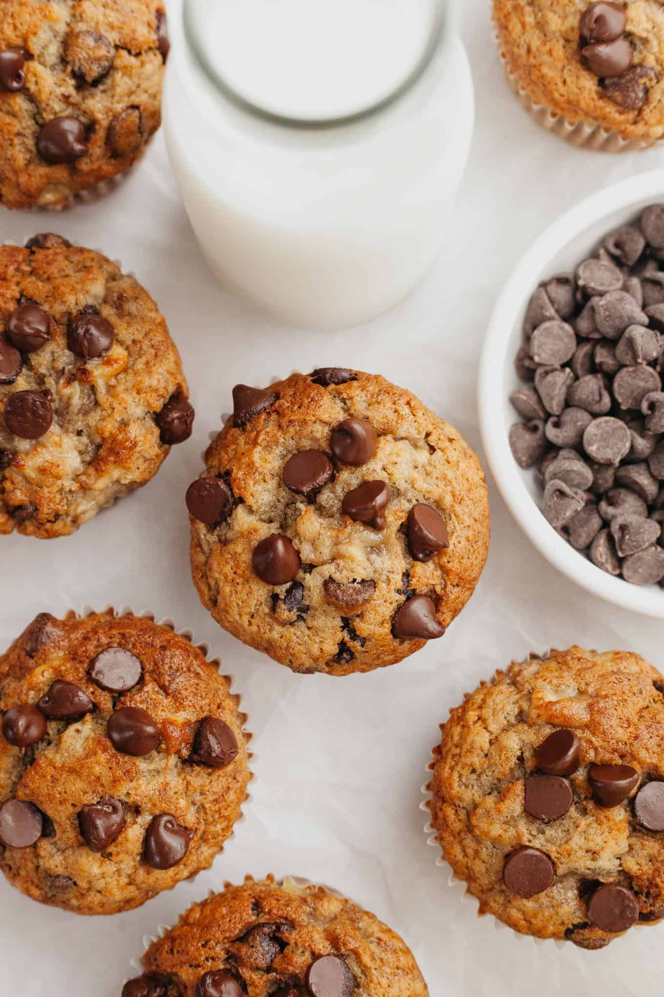 An overhead view of several muffins on a piece of white parchment paper.