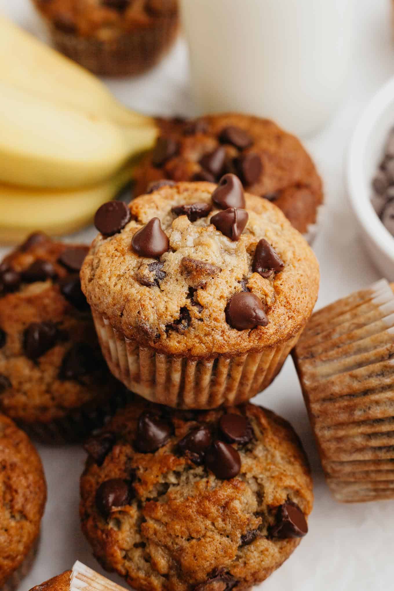 A close-up view of a banana and chocolate chip muffin sitting on a pile of muffins. 