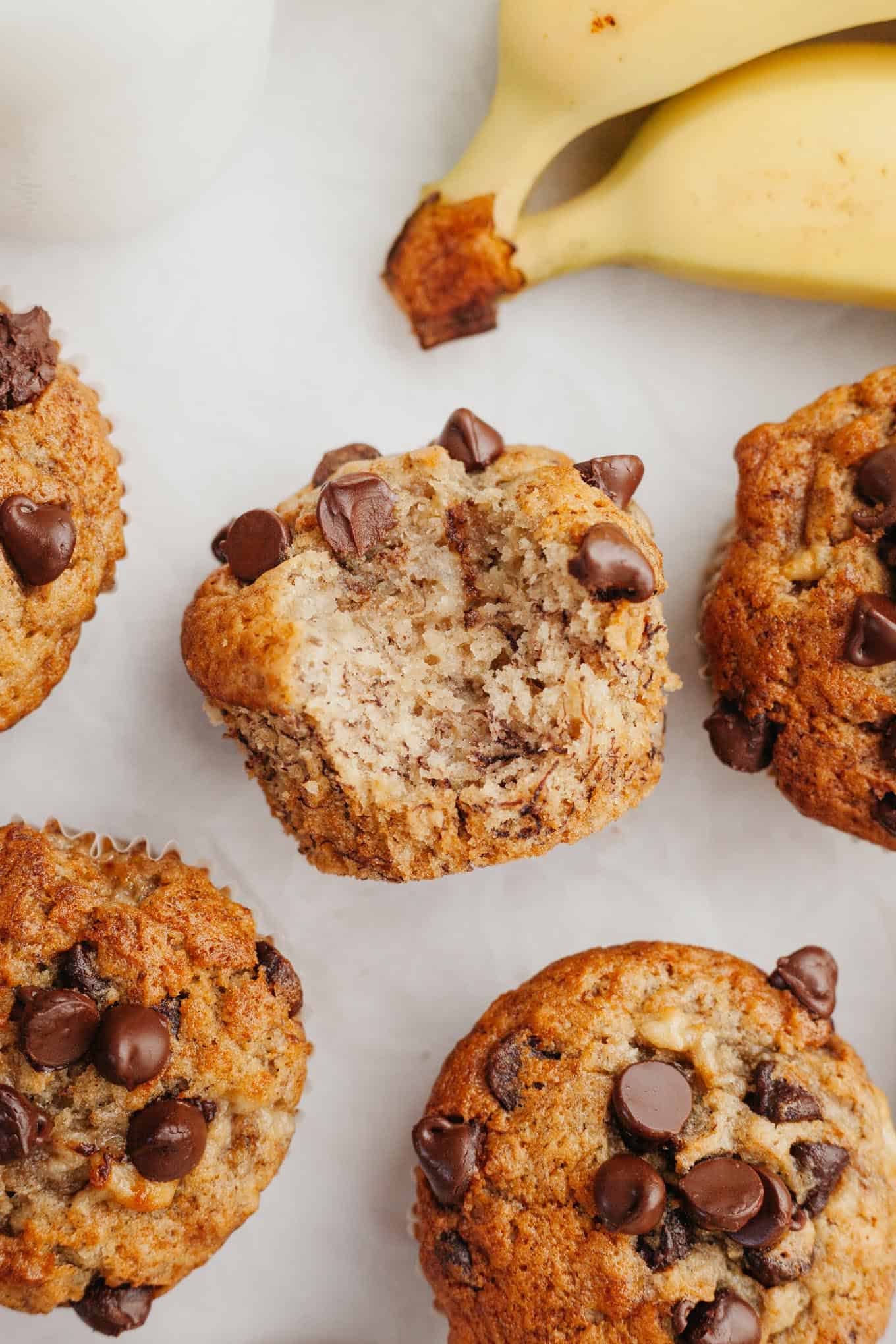 An overhead view of a banana chocolate chip muffin turned on its side with a bite missing. 