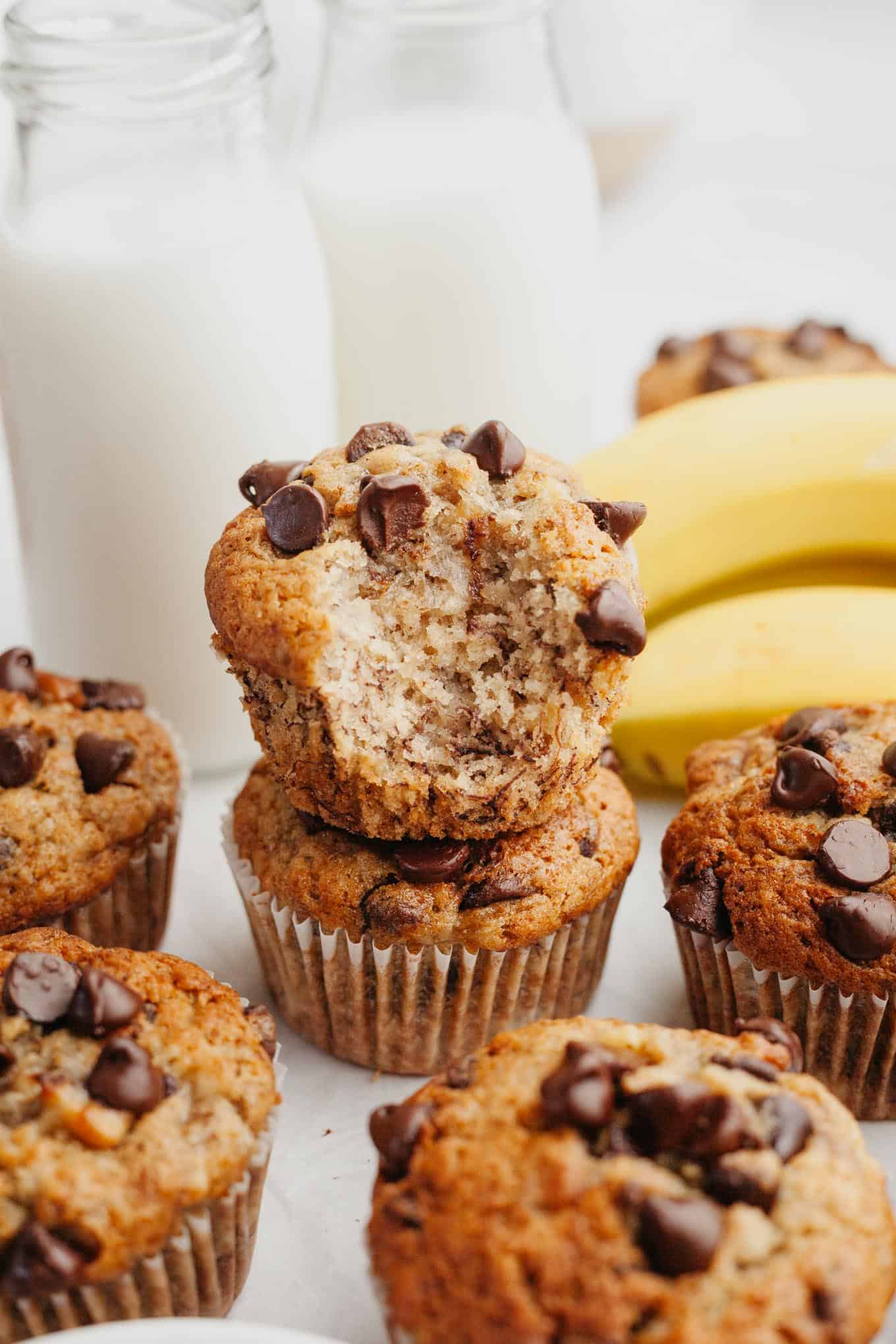 A stack of two banana chocolate chip muffins, one with a bite missing. 