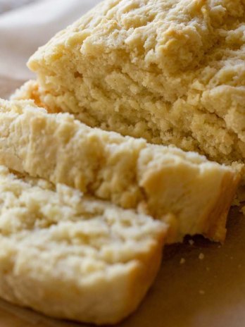 A loaf of beer bread sliced on a piece of parchment paper.