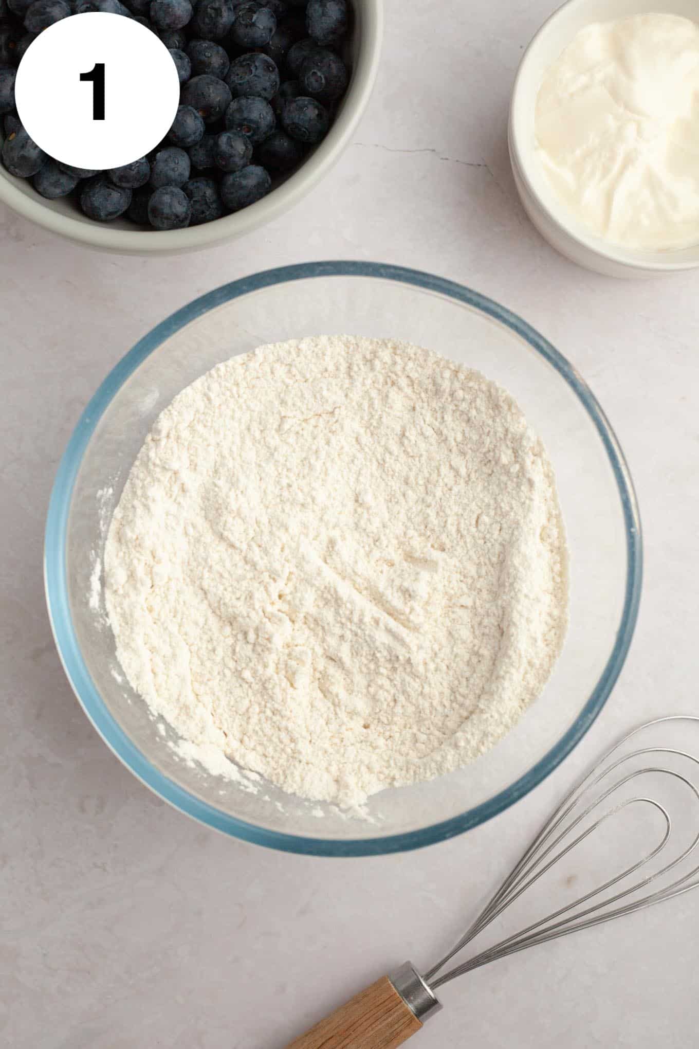 An overhead view of a flour mixture in a glass mixing bowl. 