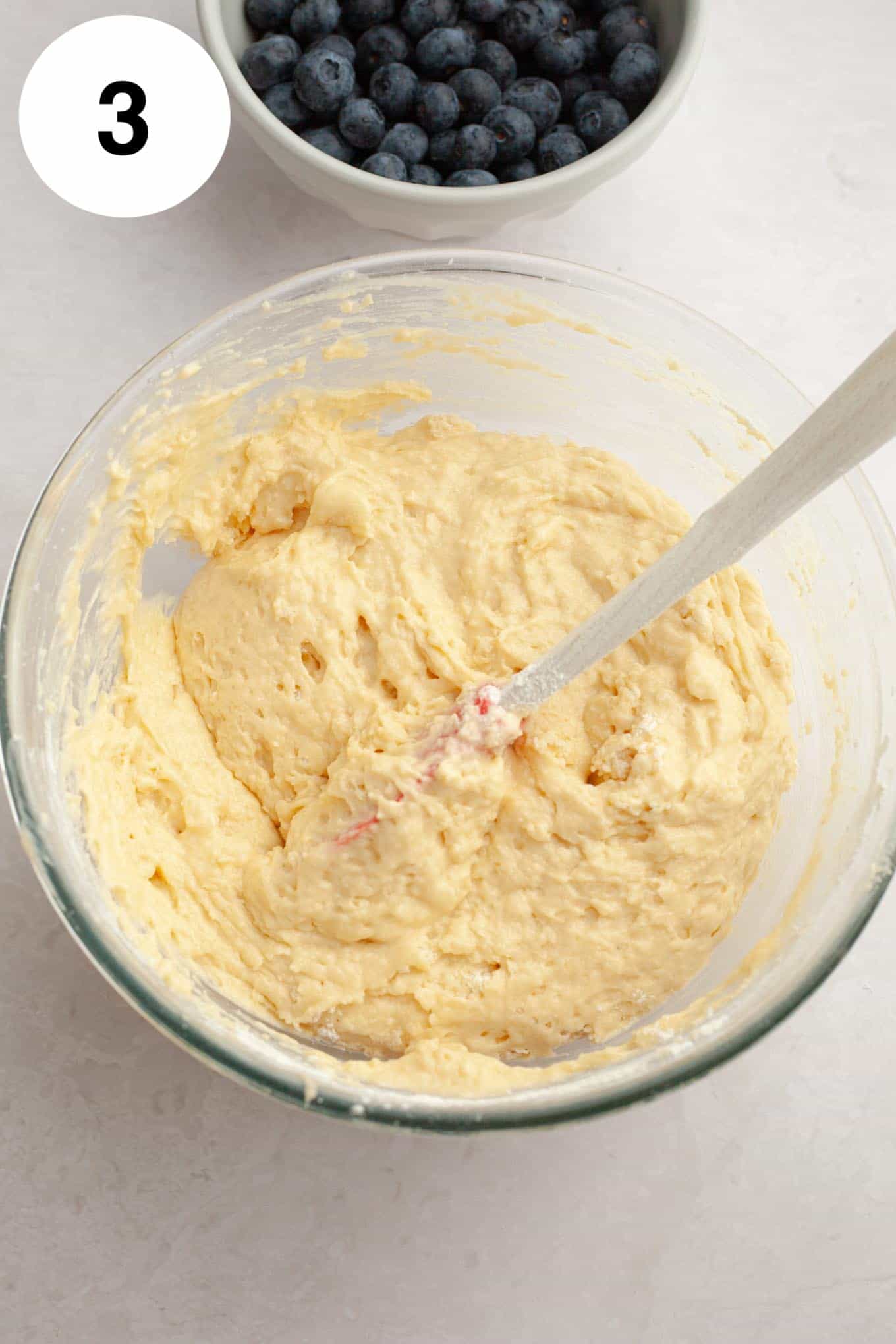 An overhead view of quick bread batter in a glass mixing bowl. 