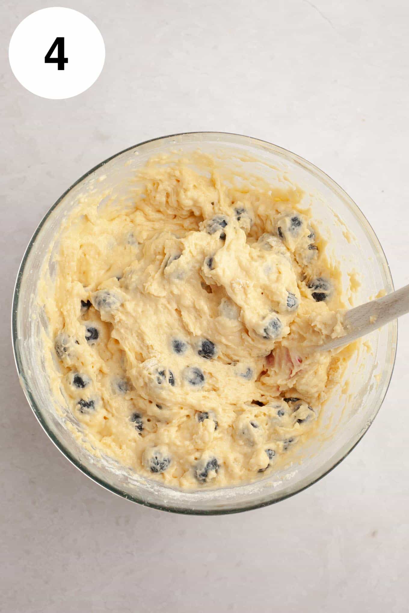 An overhead view of blueberry bread batter in a glass mixing bowl. 