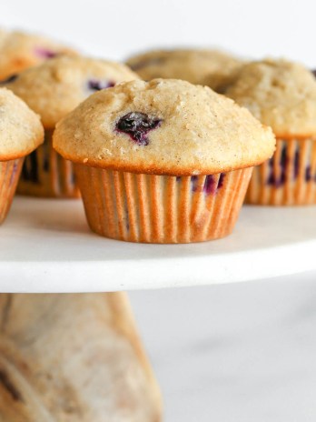 Blueberry muffins on top of a marble cake stand.