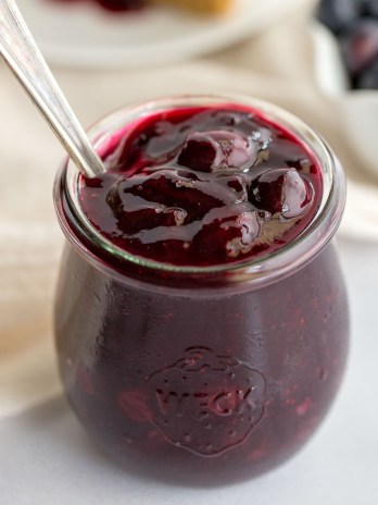 A close-up picture of a jar filled with homemade blueberry sauce.