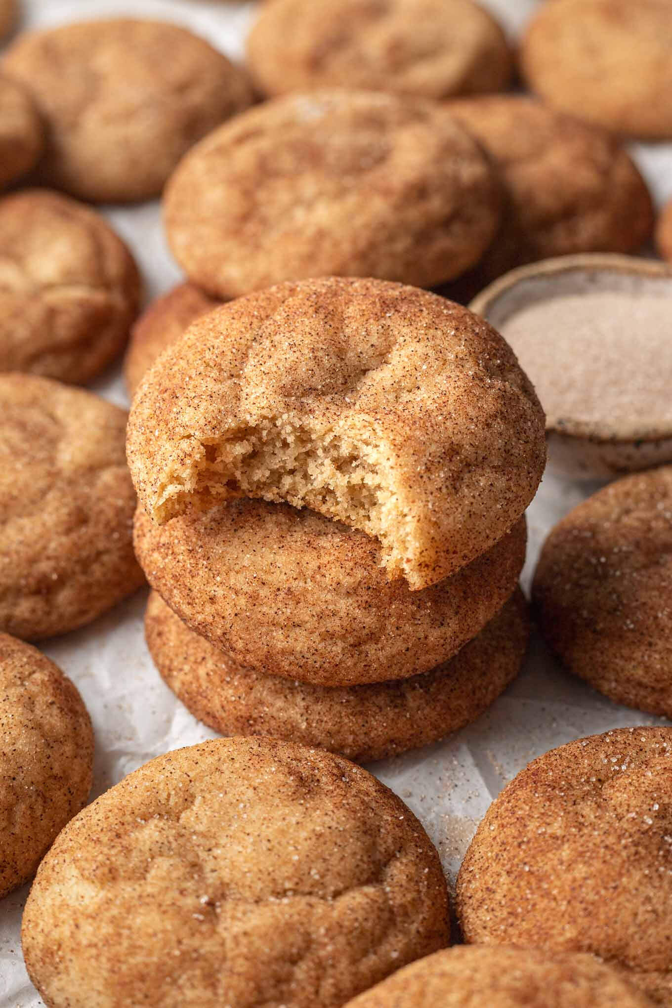 A stack of three brown butter snickerdoodles, surrounded by more cookies.