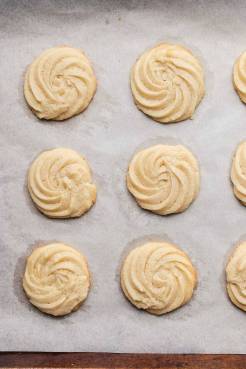 An overhead view of baked butter cookies on a parchment-lined baking sheet.
