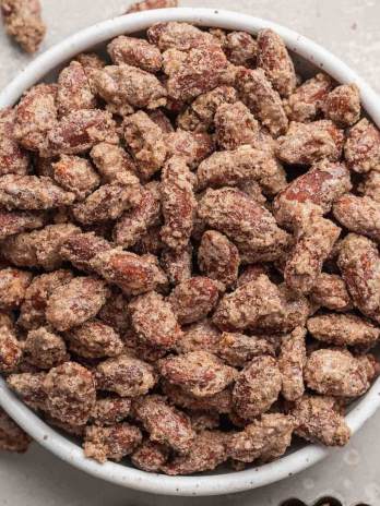 An overhead view of a white bowl filled with candied almonds.