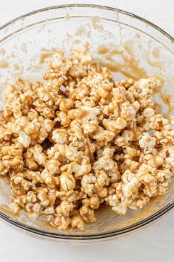 Popcorn coated in caramel sauce in a large glass mixing bowl.