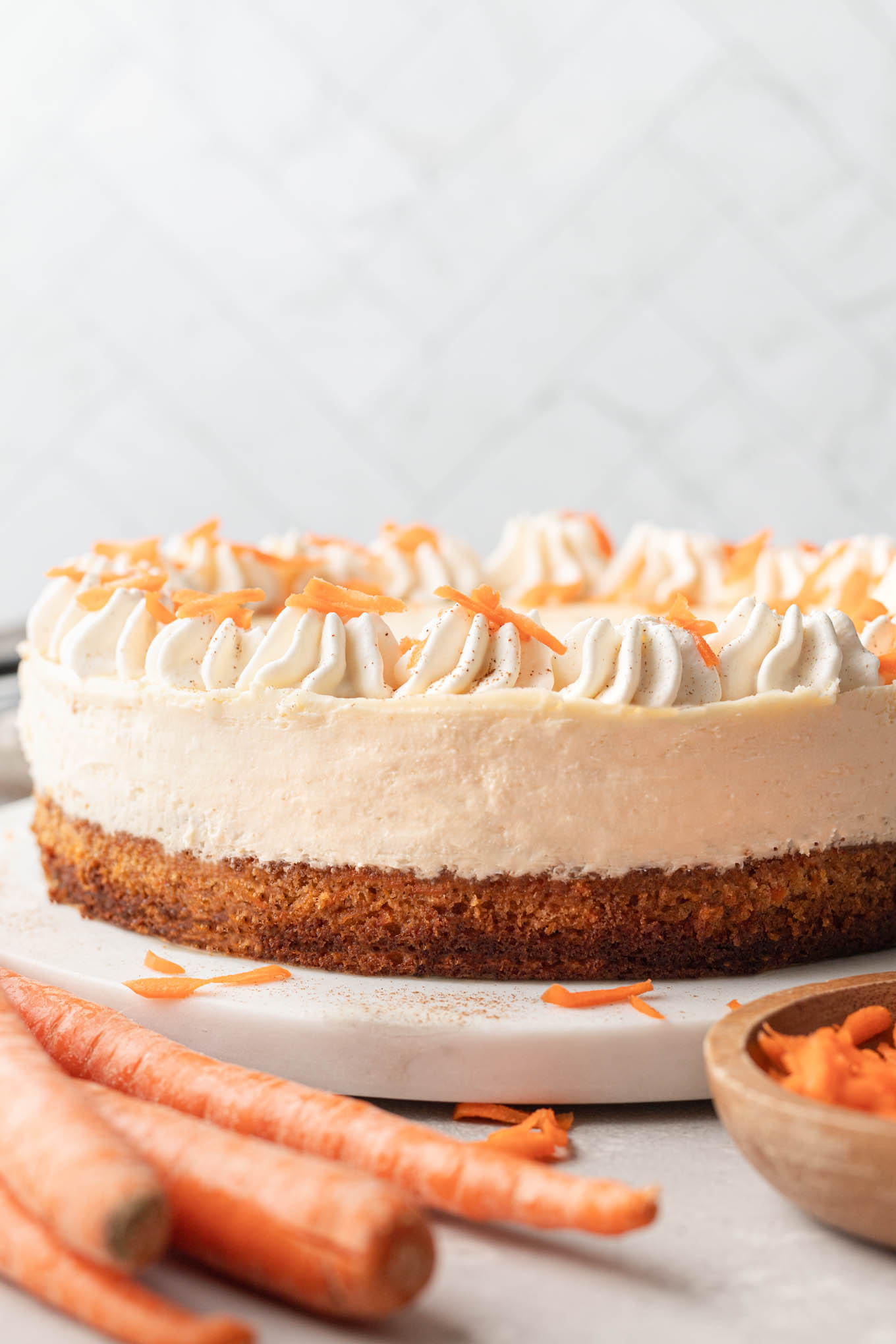A side view of a layered carrot cake cheesecake.