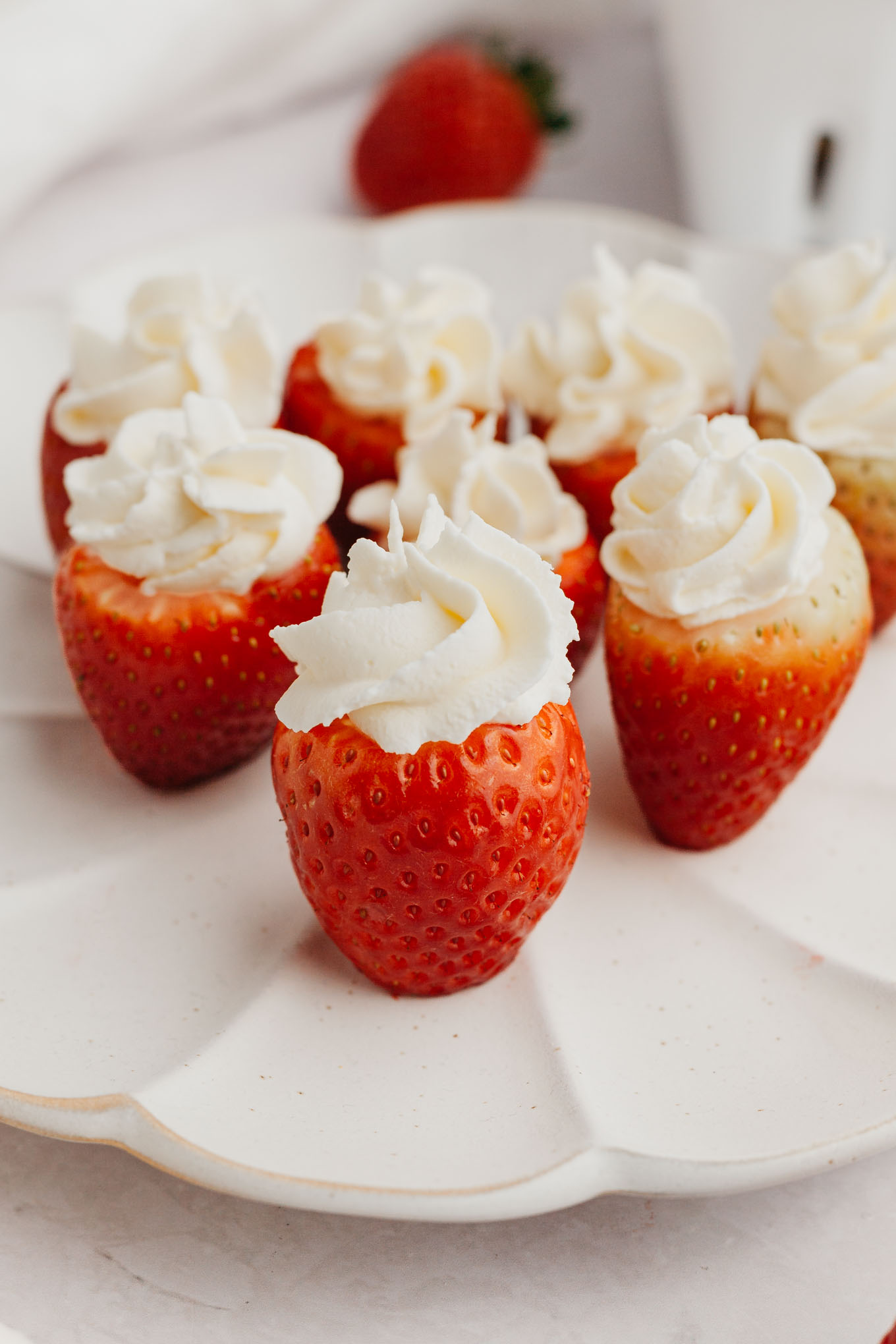 Several cheesecake stuffed strawberries on a plate.