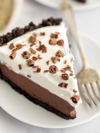 A slice of chocolate cream pie on a white plate.
