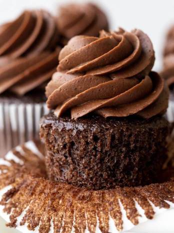 Chocolate cupcakes sitting on top of a marble cake stand.