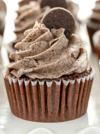 Several Oreo cupcakes lined up on a white cake stand.