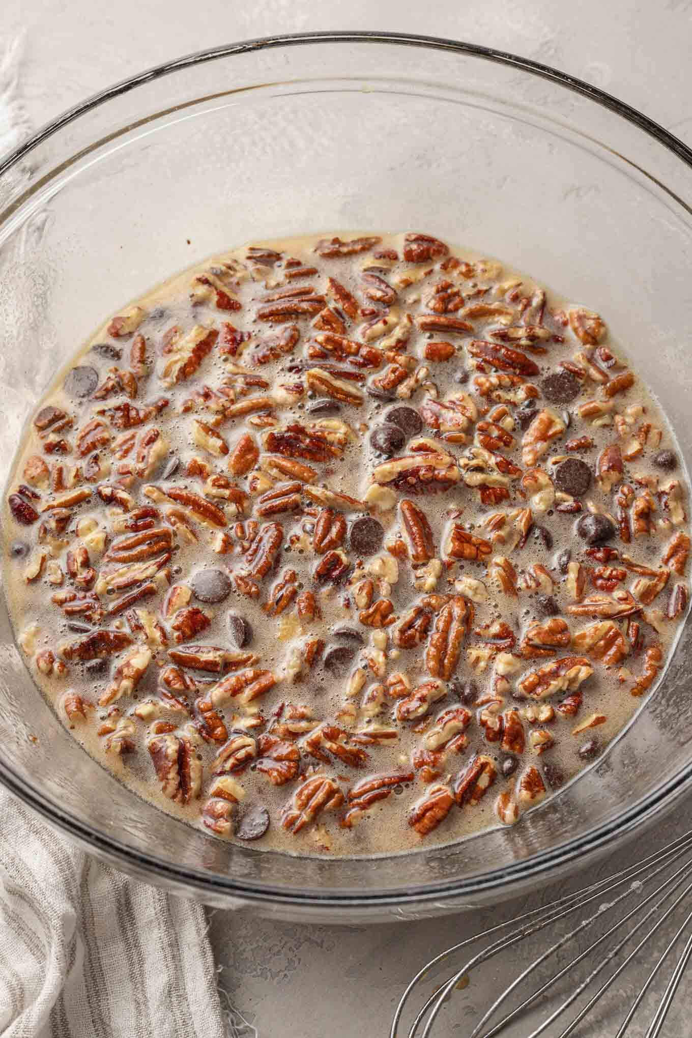 An overhead view of pecan chocolate pie filling in a glass mixing bowl.