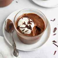 A glass filled with chocolate pudding.