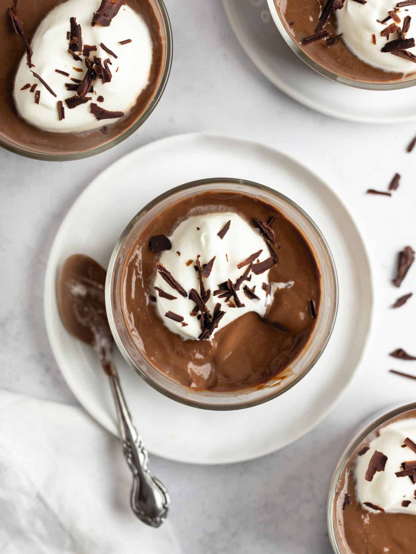 An overhead view of a pot of chocolate pudding garnished with whipped cream and chocolate shavings. 