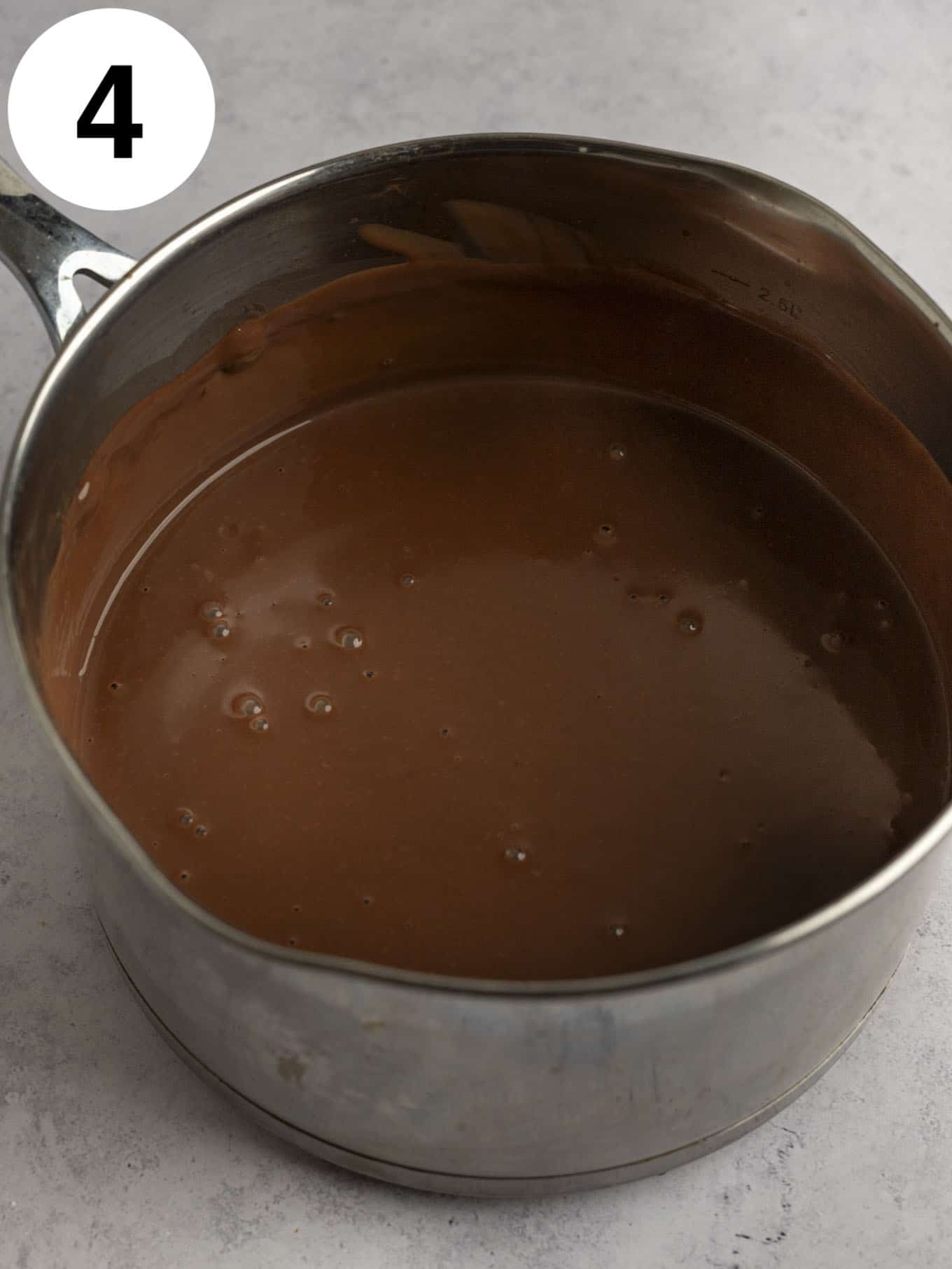 An overhead view of a chocolate pudding in a metal saucepan. 