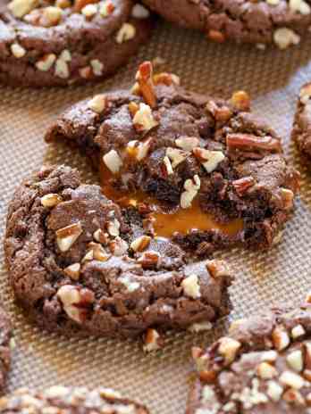 A close up view of chocolate turtle cookies on a baking sheet.