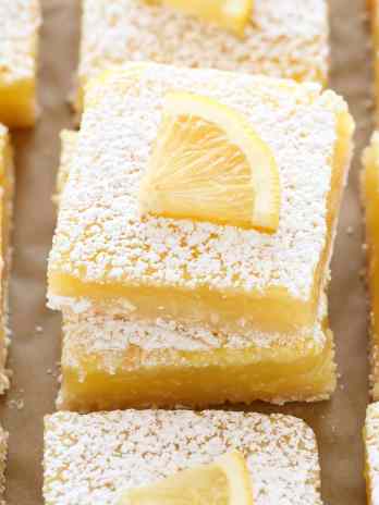 A close-up image of sliced lemon bars on a piece of brown parchment paper.
