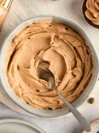 A bowl filled with coffee frosting and a spoon.