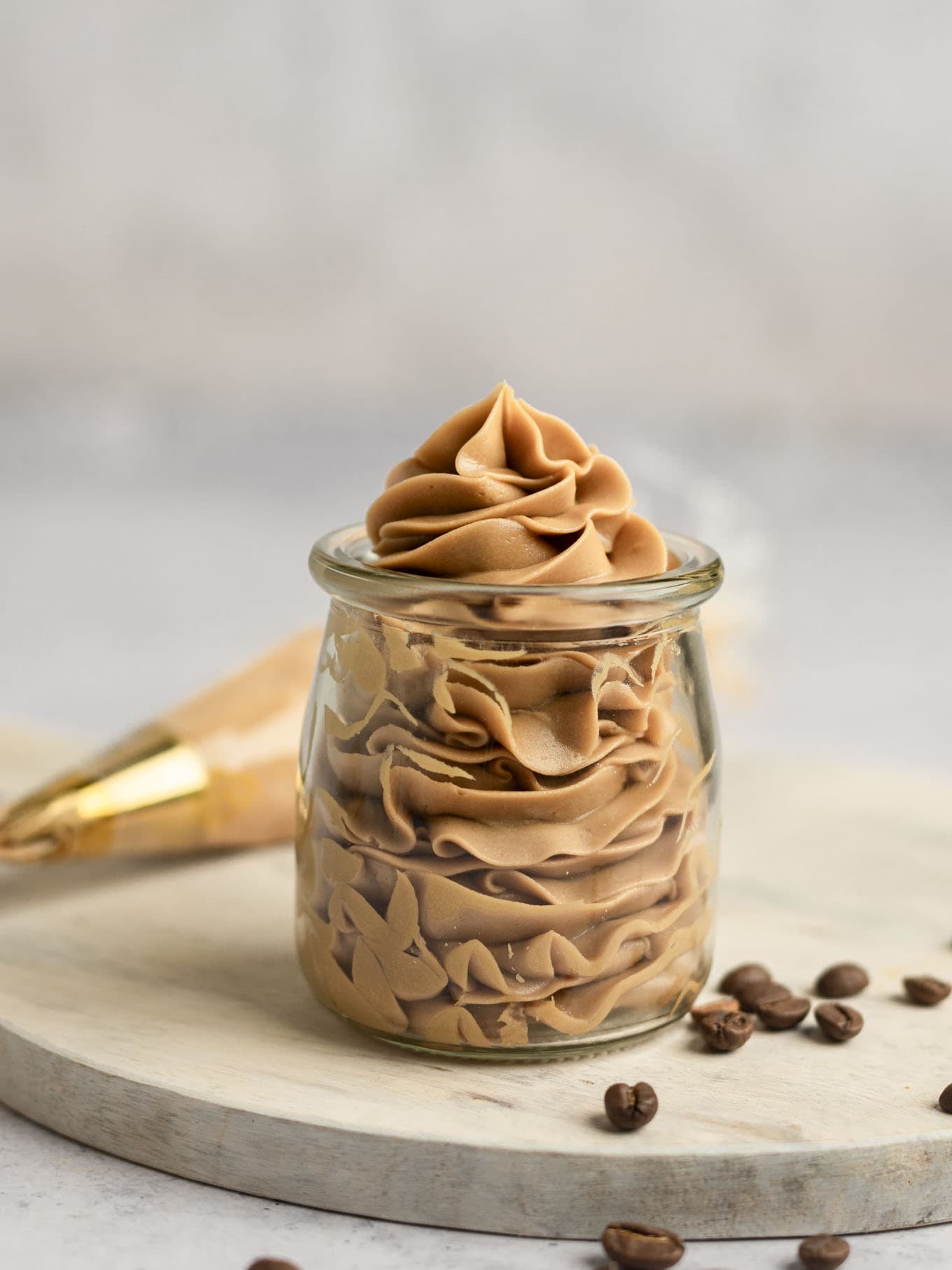 Coffee buttercream frosting piped into a clear glass jar. 