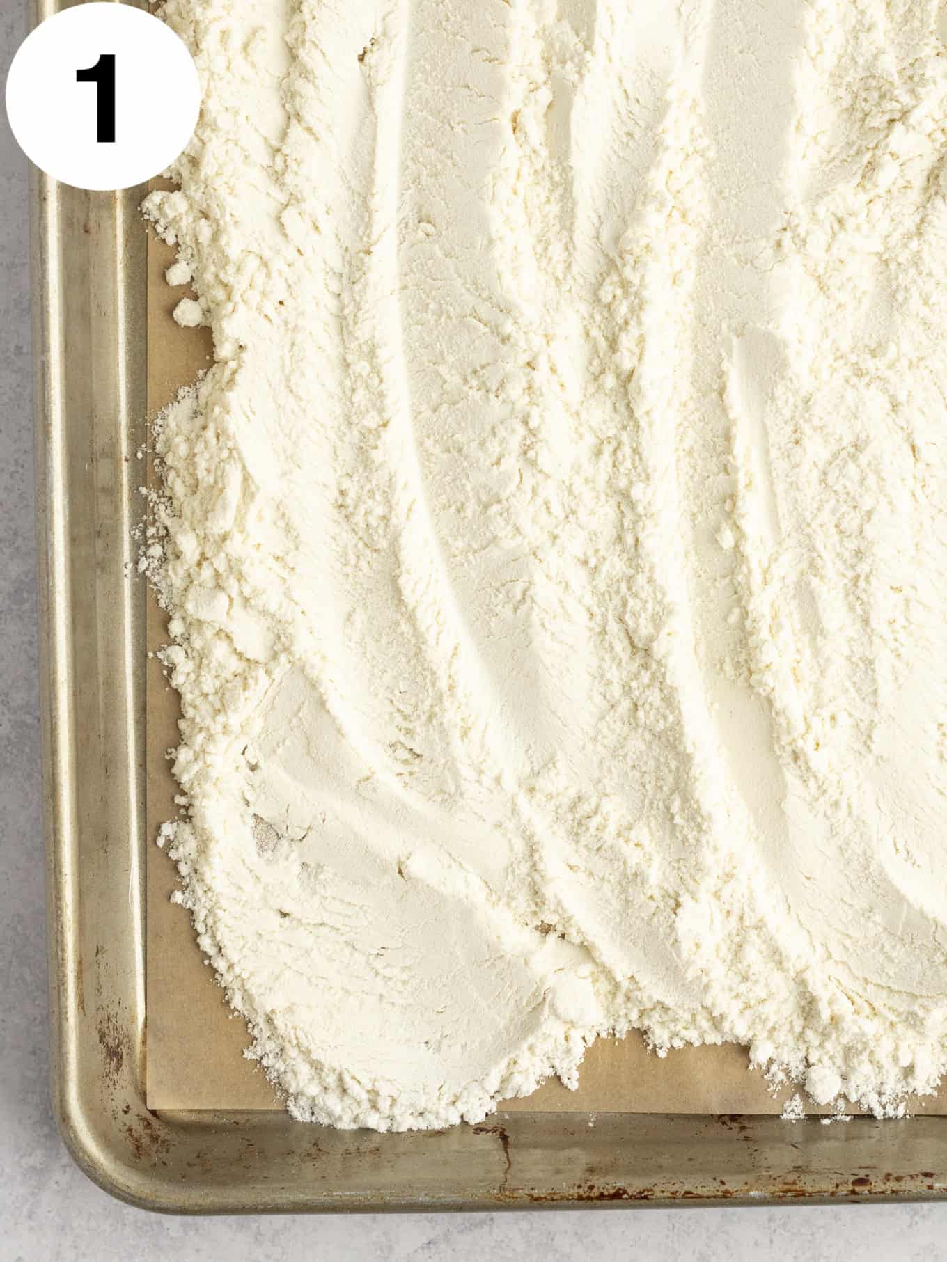An overhead view of heat treated flour on a baking sheet. 