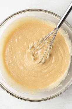 An overhead view of melted butter, sugars, and eggs mixed together in a glass mixing bowl.
