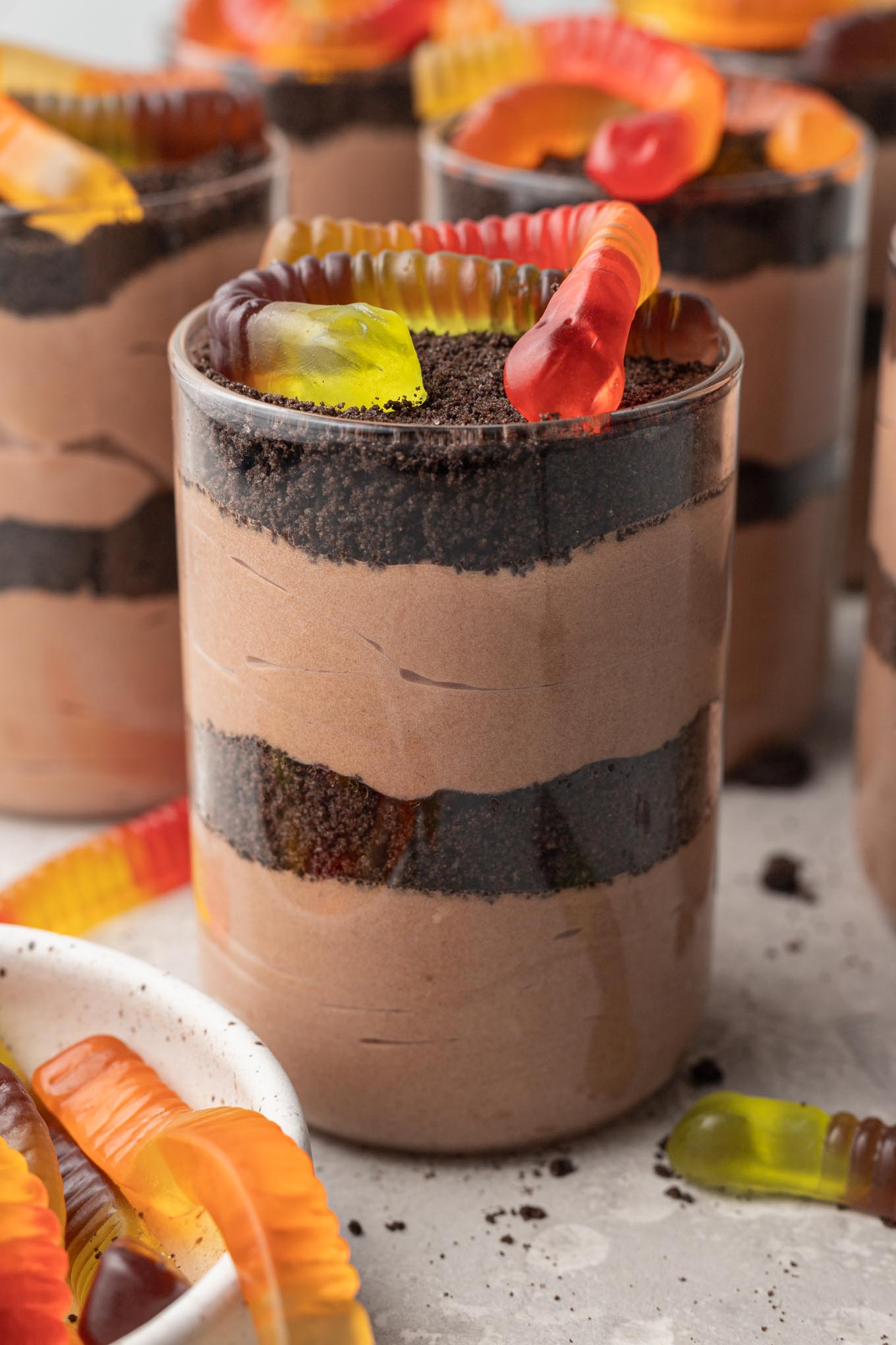Layered Oreo dirt cups with gummy worms on top.