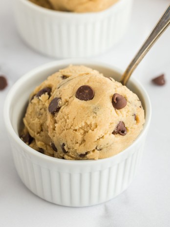A close-up picture of edible cookie dough inside of a white ramekin.