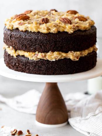 A layered German Chocolate Cake on top of a marble cake stand.