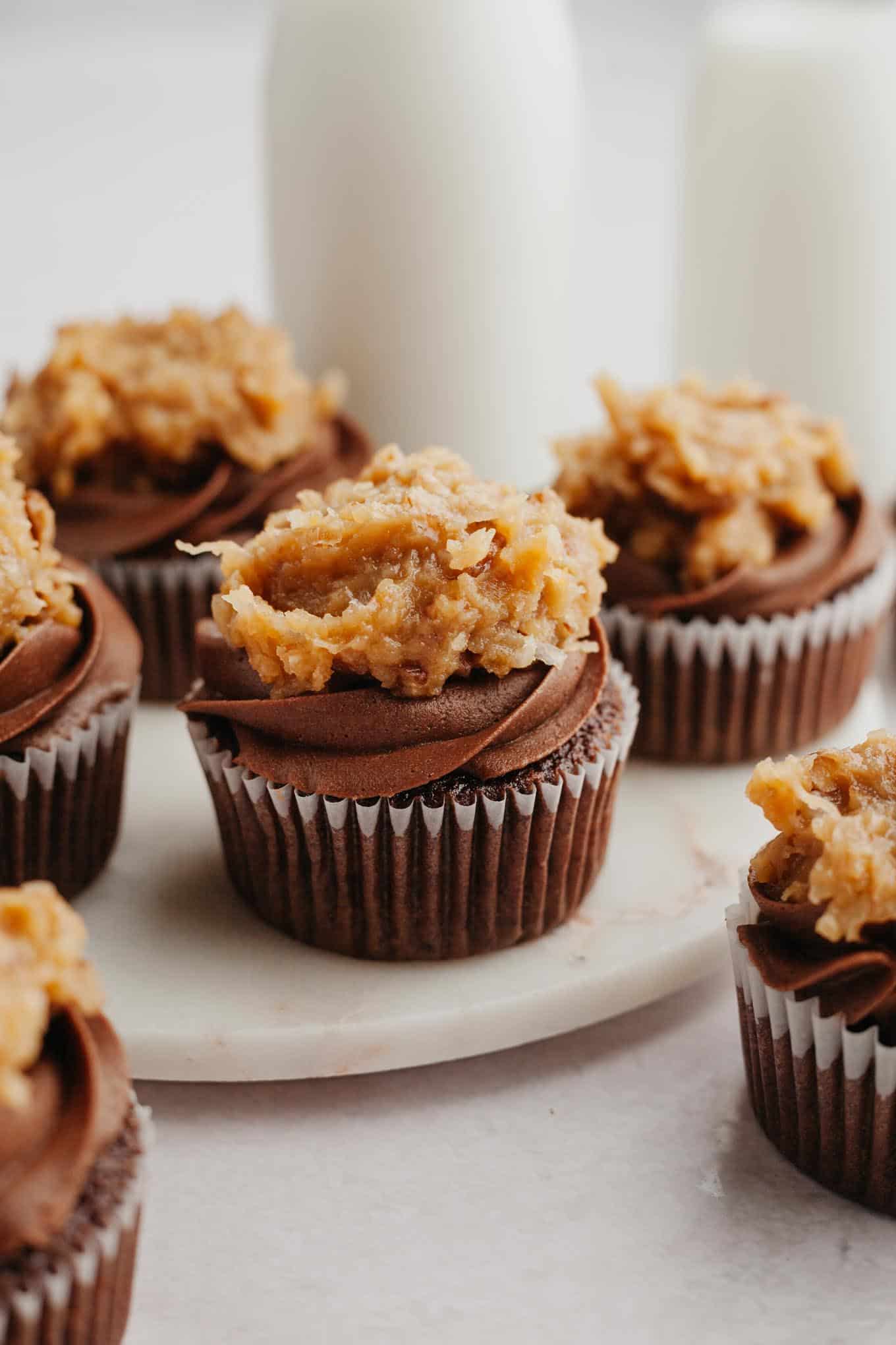 Frosted German chocolate cupcakes on a marble serving platter.