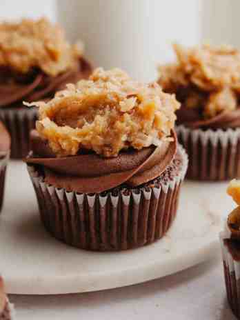 Several German Chocolate cupcakes on a marble serving plate.