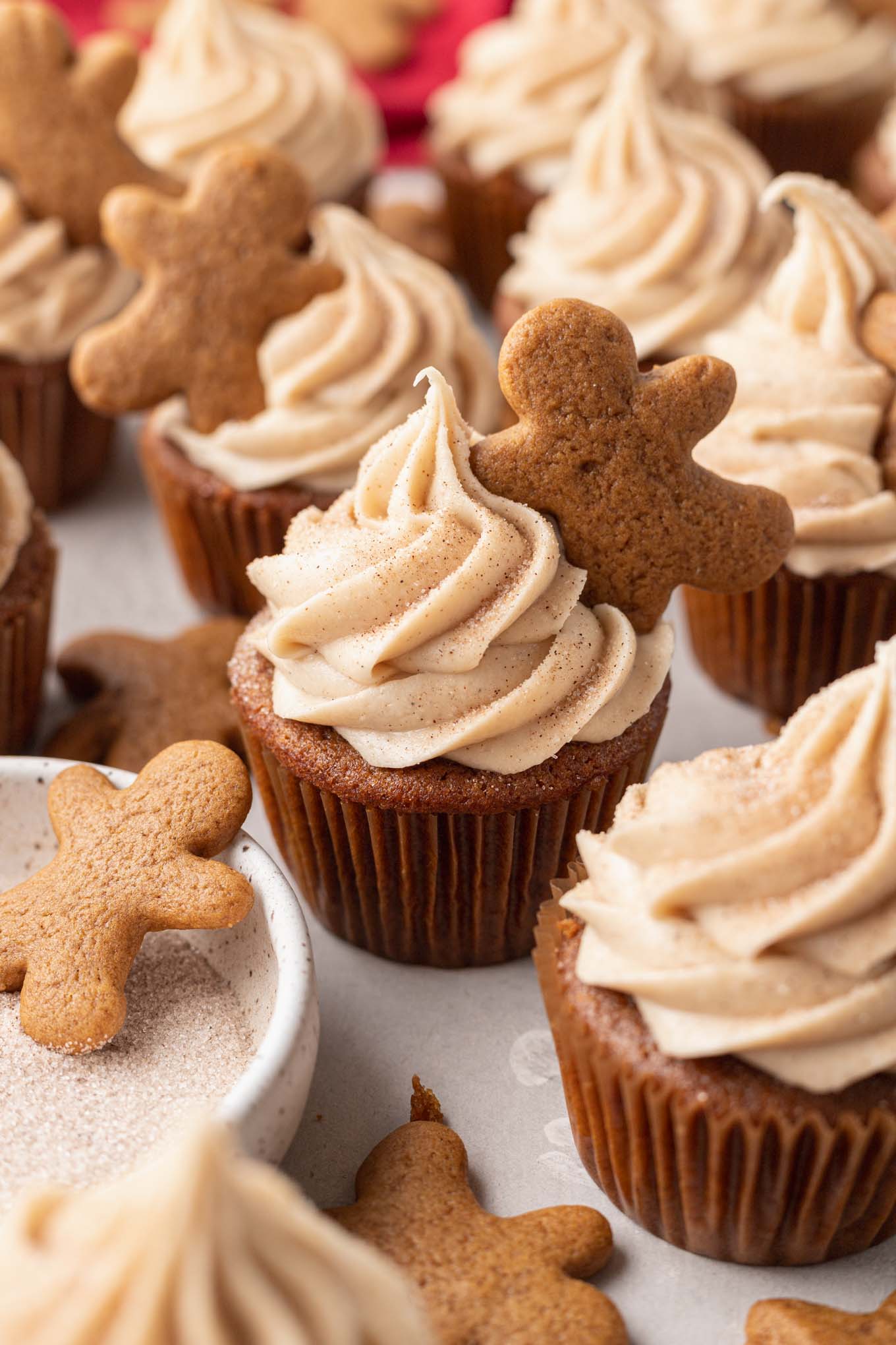 Gingerbread cupcakes piped with cinnamon cream cheese frosting and topped with a mini gingerbread cookie.