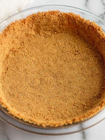 A graham cracker crust pressed into a glass pie dish.
