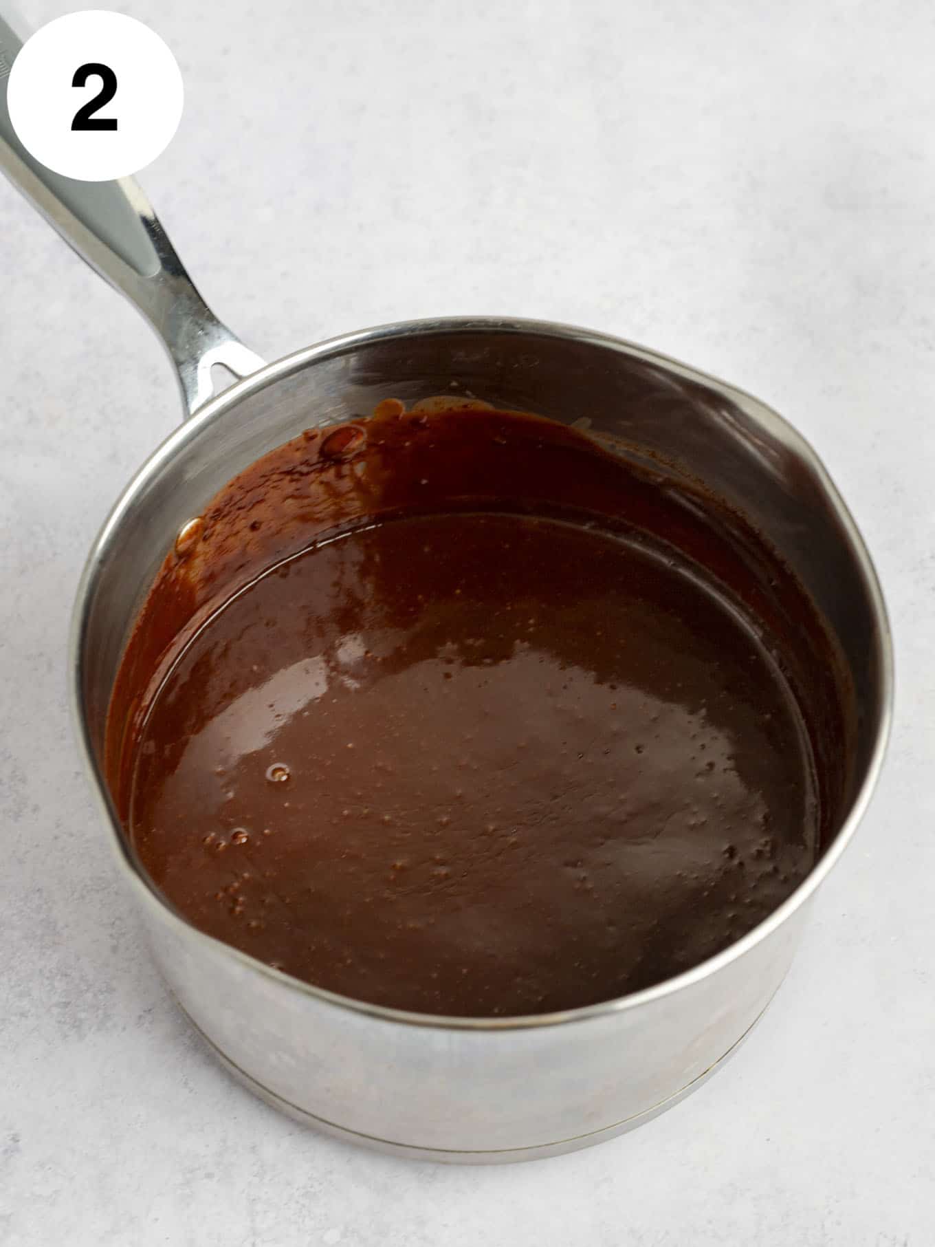 A metal saucepan full of classic fudge sauce.  