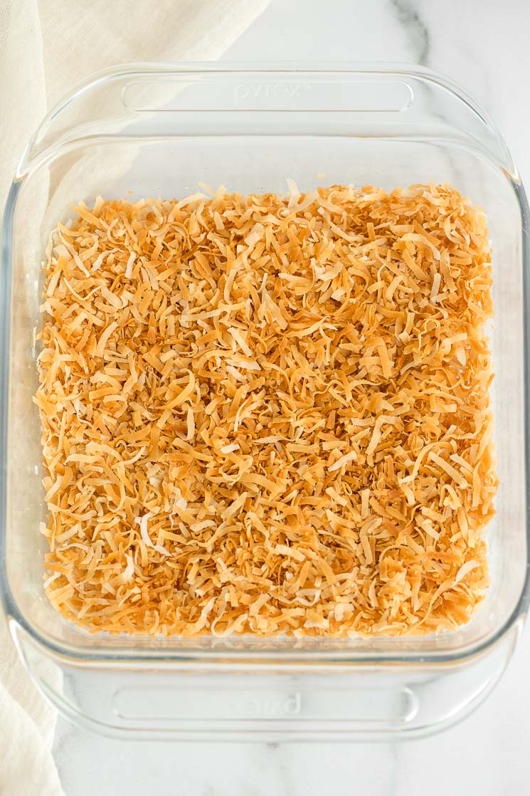 A glass baking dish with toasted coconut covering the bottom. 