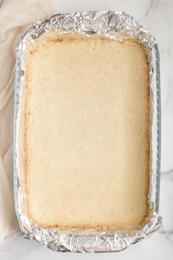 The baked shortbread crust in a pan lined with aluminum foil.